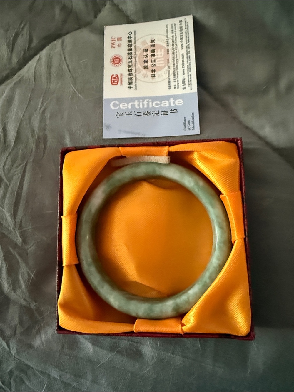 A Chinese green jade bangle bracelet in a presentation box with certificate.